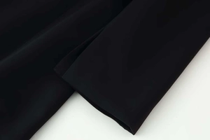 Détail de la manche d'une robe tissée noire avec coutures invisibles et ourlet épuré