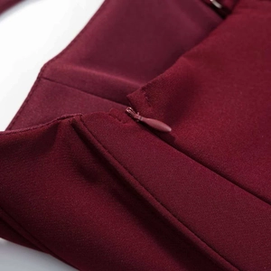 Détail de la fermeture éclair invisible sur une robe rouge vin au fini brillant