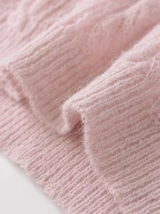 Close-up of pink knit fabric featuring vertical stripes and soft cable textures