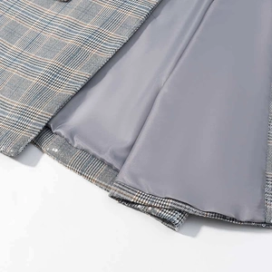 Detailed close-up of grey plaid blazer fabric with smooth inner lining and quality stitching