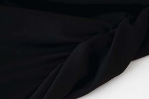 Close-up of black textured fabric detail showing the delicate knit and soft chiffon folds
