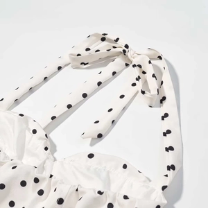 Gros plan sur le col licou à pois noirs d'un ensemble d'été blanc pour femme