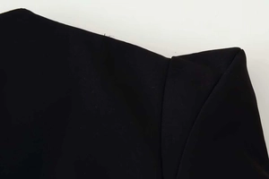 Gros plan détaillé sur la texture du tissu noir et les coutures de l'encolure du vêtement