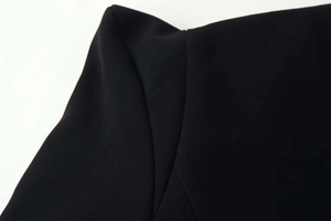 Gros plan sur la texture du tissu noir et les coutures soignées d'une robe longue