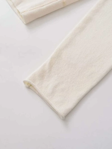 Detailopname van beige gebreide stof en de zachte rolzoom aan de mouwopening