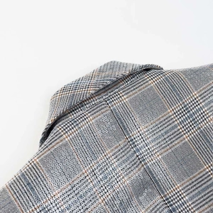 Detailed close-up of grey plaid notched lapel showing fine texture and sewing craft