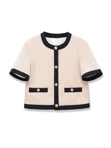 Détail du cardigan crème élégant avec bordures noires et boutons dorés décoratifs