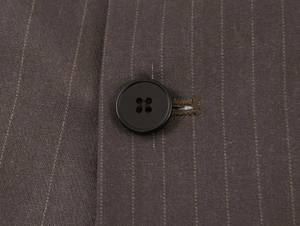 Detail of black four-hole button and fine pinstripe texture on brown blazer