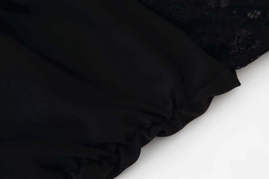 Close-up detail of black lace stitching and elastic pleated hem on a halter dress