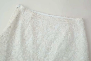 Close-up of ivory crochet lace embroidery and invisible side zipper on an elegant skirt