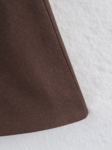 Macro detail of dark brown fabric showing precise single-needle stitching and fine texture