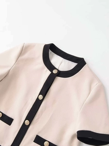 Détail du cardigan beige à col rond avec bordure noire et boutons dorés élégants