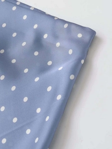 Detailed macro shot of blue satin fabric with white polka dots showing smooth texture