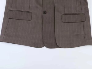 Detailed view of brown striped blazer featuring flat flap pockets and dark button closure