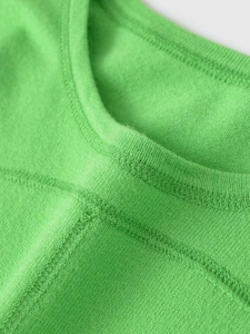 Detailopname van felgroene gebreide top met ronde hals en dubbele stikselafwerking
