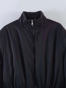 Close-up of black stand collar jacket featuring smooth fabric and silver metal zipper detail