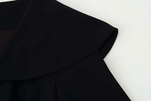 Close-up detail of smooth black fabric and large ruffle lapel collar on the wide-leg suit
