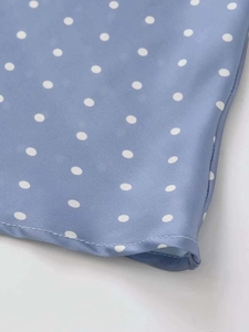 Close-up of light blue satin fabric with white polka dots and high-quality stitching