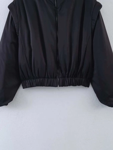 Detail shot of structured shoulders and elastic waist on a black zipper jacket