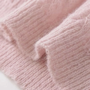Close-up of pink cable knit fabric showing soft mohair texture and ribbed weave detail