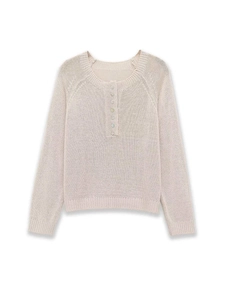 Detail of soft cream knit sweater with decorative iridescent buttons and ribbed cuffs