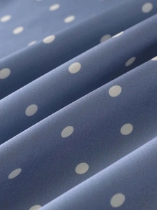 Detailed macro view of blue satin fabric with white polka dots and smooth texture