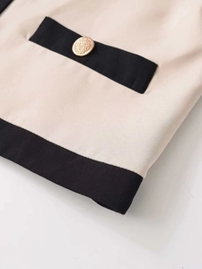 Détail du tissu beige avec bordure contrastée noire et bouton doré élégant