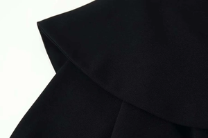 Macro detail of black crepe fabric texture and layered ruffles on wide-leg jumpsuit