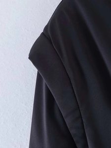Detail shot of smooth black satin jacket fabric with soft pleats and elegant sheen