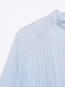 Detail of light blue pinstripe shirt showing high neck design and diagonal shoulder seams