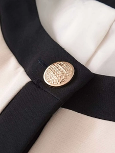 Gros plan d'un bouton doré texturé sur le détail d'un cardigan bicolore chic
