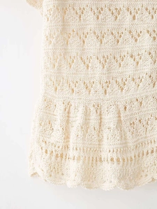 Detailed macro view of cream-colored open-knit cotton fabric with ruffled hemline