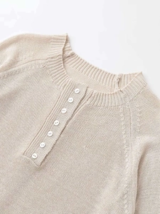Detail of oatmeal knit sweater featuring a buttoned crew neck and soft ribbed texture