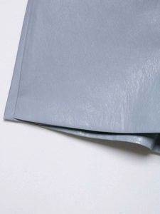 Vue détaillée de la texture du cuir bleu clair et des coutures d'une jupe asymétrique