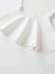 Detail shot of the ribbed knit fabric and white ruffled hem on the elegant women's top