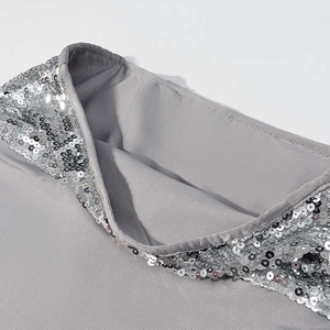 Close-up of silver sequins sewn on grey fabric for a shimmering two-piece skirt set