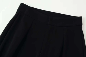 Detailed view of high-waisted black wide-leg trousers with pleated waist design
