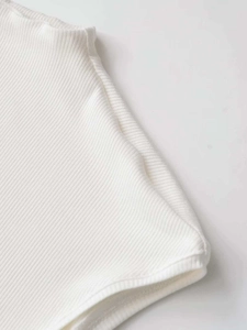 Close-up of white rib-knit fabric texture and stitching details on a summer top