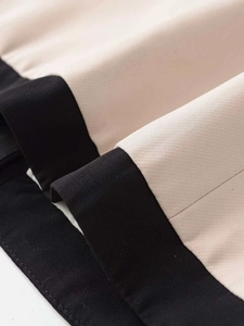 Gros plan des coutures contrastées sur tissu sergé beige et noir montrant les finitions