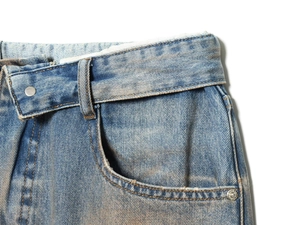 Detailed view of women's distressed denim jeans with asymmetric waist and metal button