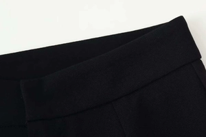 Macro detail of high-quality black wide-leg trousers waist showing smooth fabric texture
