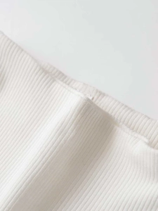 Close-up of white ribbed knit fabric showing vertical textures and high-quality stitching