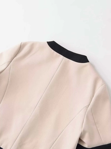 Détail du col d'un blazer beige avec un élégant liseré contrasté noir de qualité