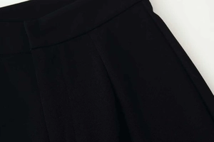 Detailed view of the pleated waistband on these black high-waist wide-leg suit trousers