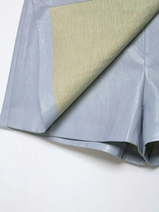 Détail en gros plan du short en similicuir bleu clair avec doublure intérieure jaune pâle