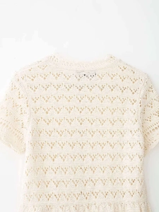 Close-up of cream crochet knit short sleeve top showing intricate lace texture and round neck