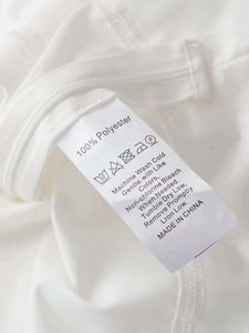 Detail shot of the care label and zipper on a white 100% polyester peplum t-shirt