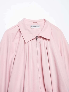 Detail view of pink bubble sleeve shirt showing the zipper neckline and brand label