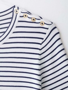 Close-up of nautical style navy striped knit top with decorative gold buttons on shoulder