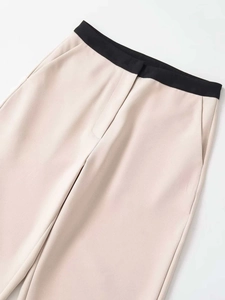 Détail d'un pantalon beige taille haute avec ceinture noire contrastée et poches latérales